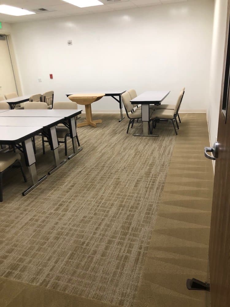 Shared meeting room with freshly shampooed carpet and tables reset after a scheduled clean