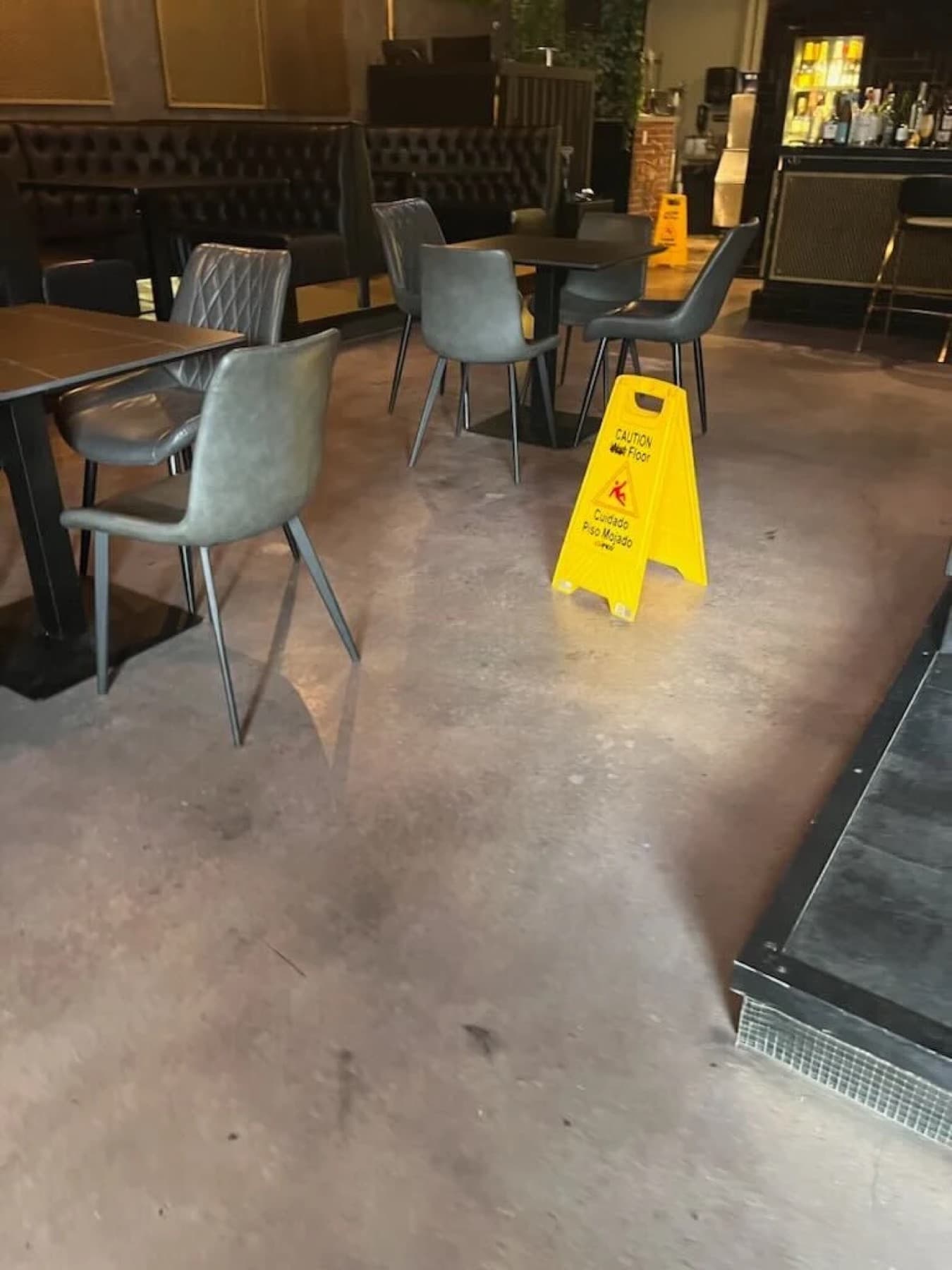 Restaurant bar floor being cleaned, wet floor caution sign in place