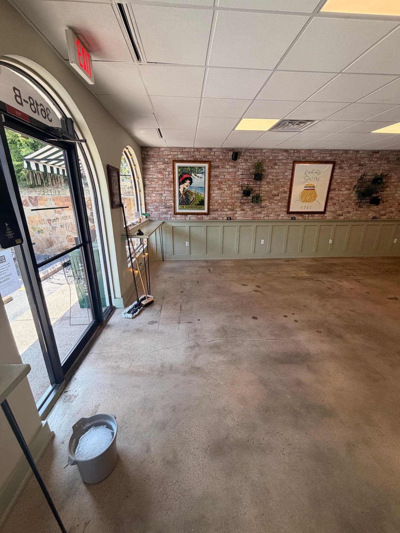 Dull, matte café dining-room concrete floor with a mop bucket in the frame, before restoration
