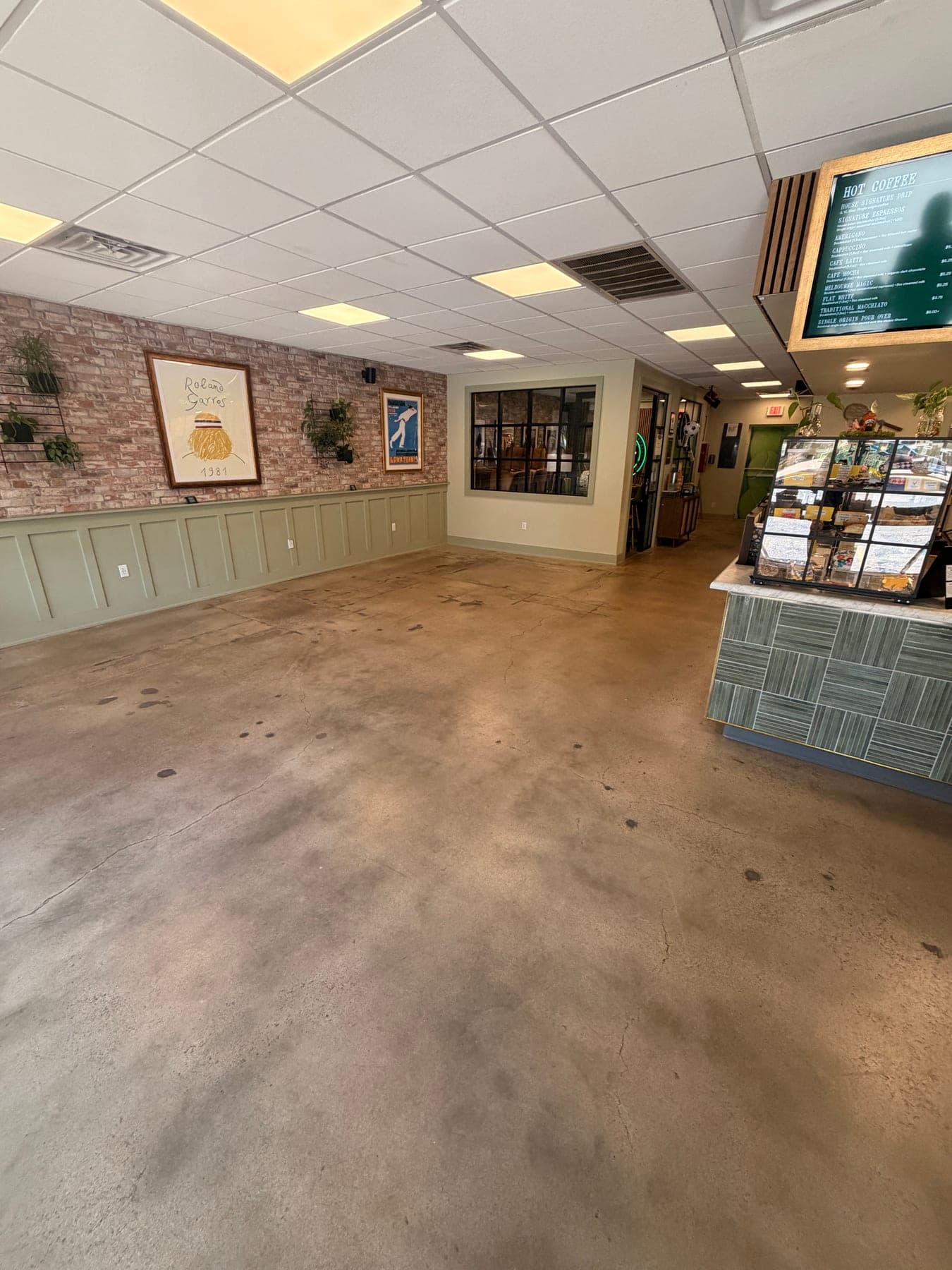 Dull, worn concrete floor across a cafe dining room before cleaning
