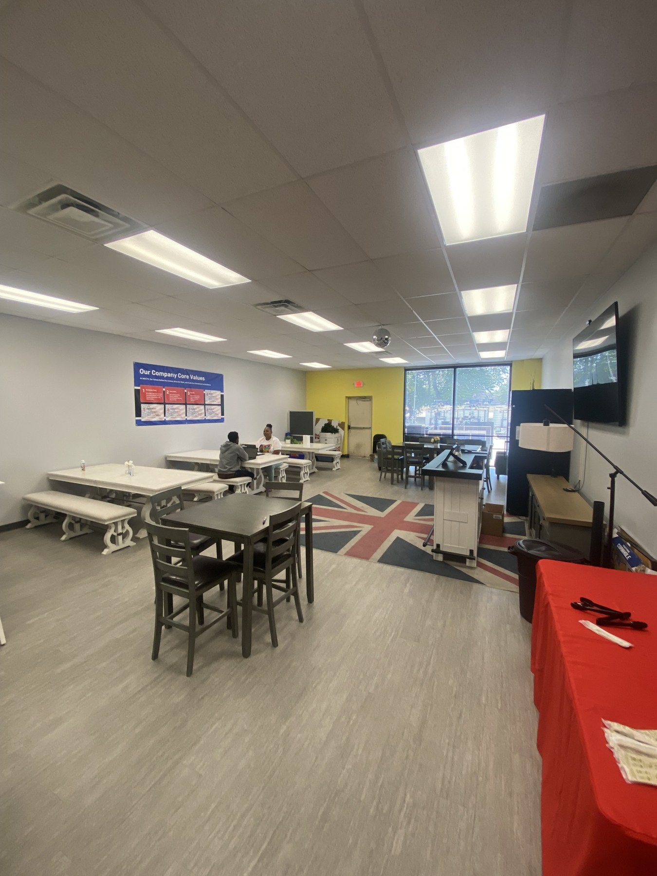 Employee break room with farmhouse tables, bar-height tables and a grey wood-look plank floor