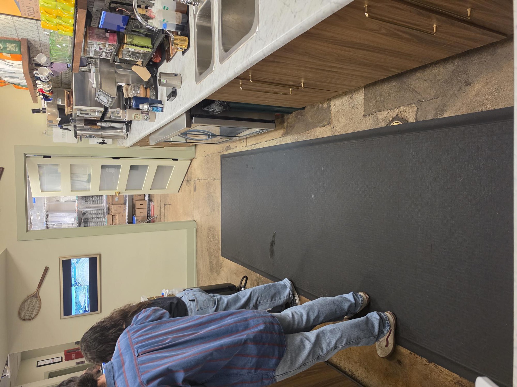 Coffee shop back corridor with black anti-fatigue mats down the middle and espresso machines on the right